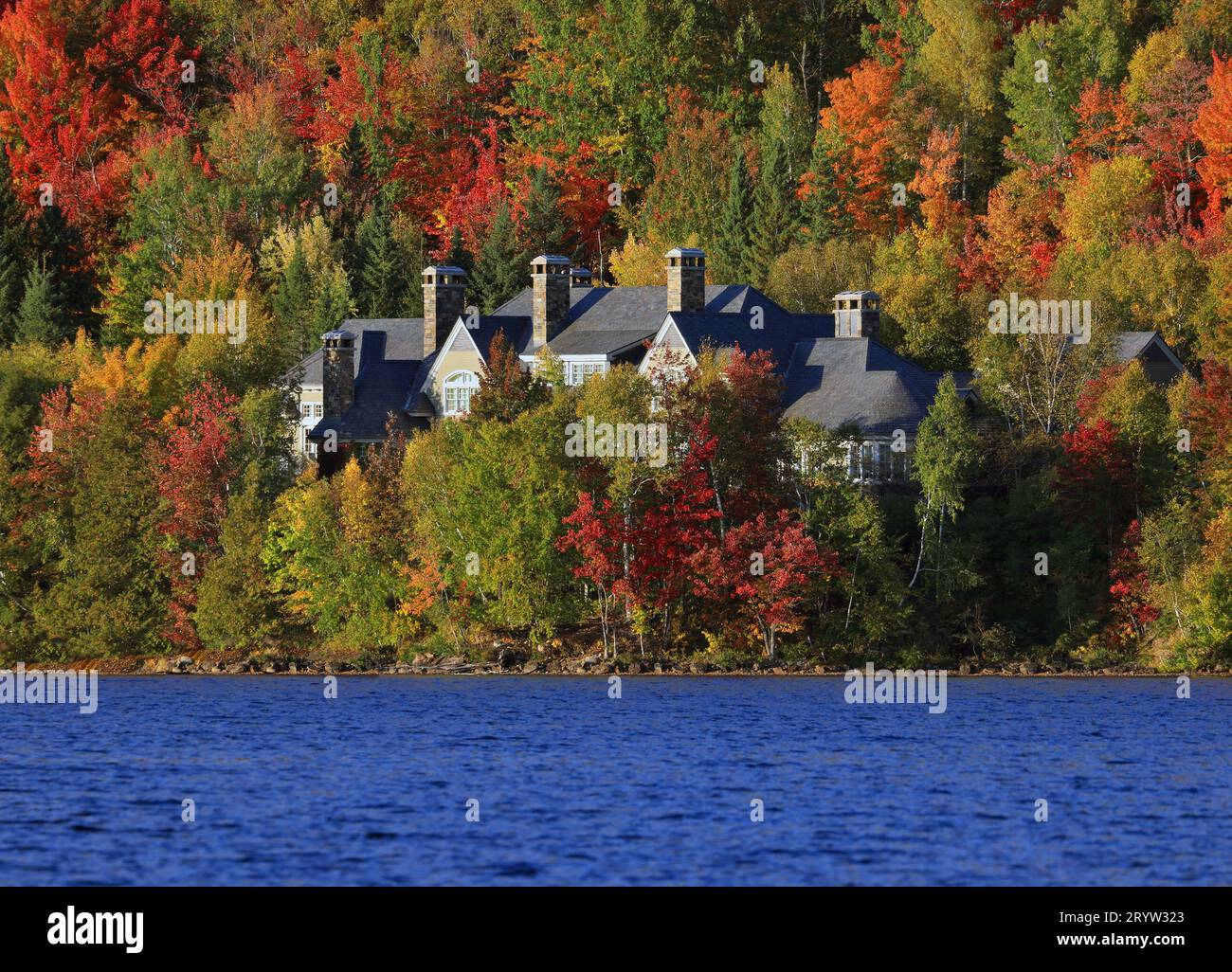 Haus an der Grenze des Sees umgeben von Herbstfarben in Mont Tremblant, Quebec, Kanada Stockfoto