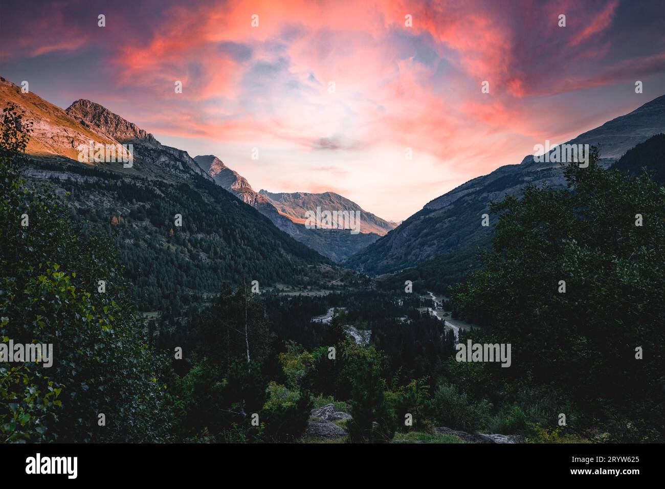 Ein leuchtend roter Sonnenuntergang, der den Horizont über eine Reihe von Bergen erleuchtet. Stockfoto