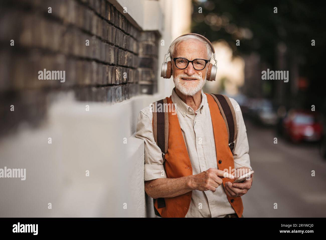 Nahaufnahme eines älteren Mannes, der Musik über Kopfhörer auf der Straße hört. Stockfoto