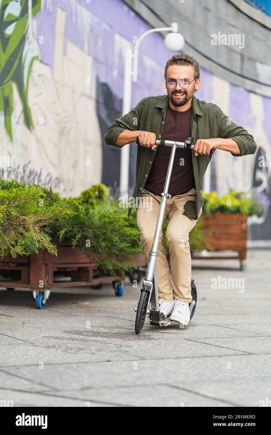 Mann auf einem Roller, der Stunts mit einem großen Roller macht. Mit einem hübschen und selbstbewussten Auftreten zeigt er seine Fähigkeiten A Stockfoto