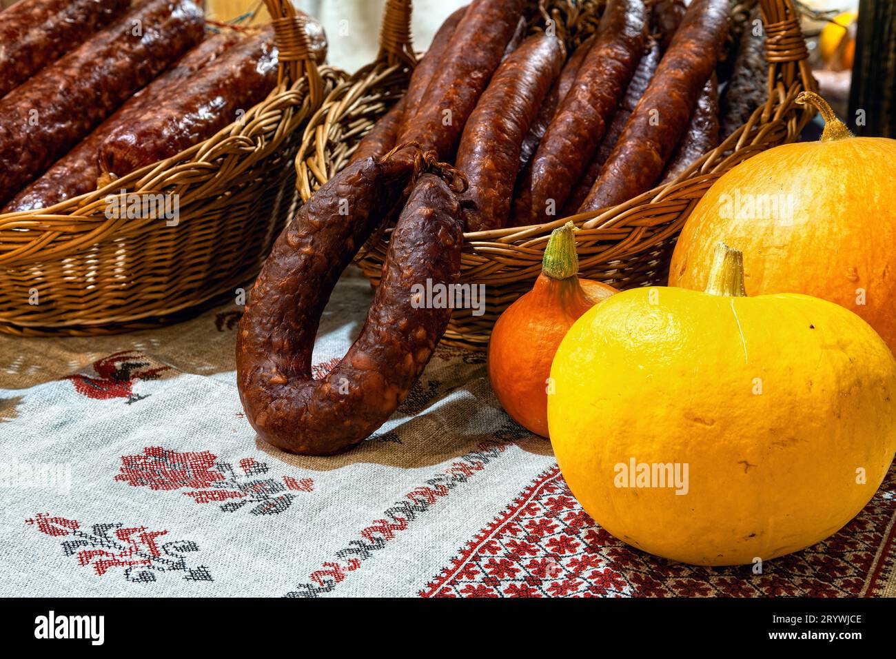 Hausgemachte ukrainische Wurst auf traditioneller bestickter Tischdecke wird auf dem Markt verkauft. Stockfoto
