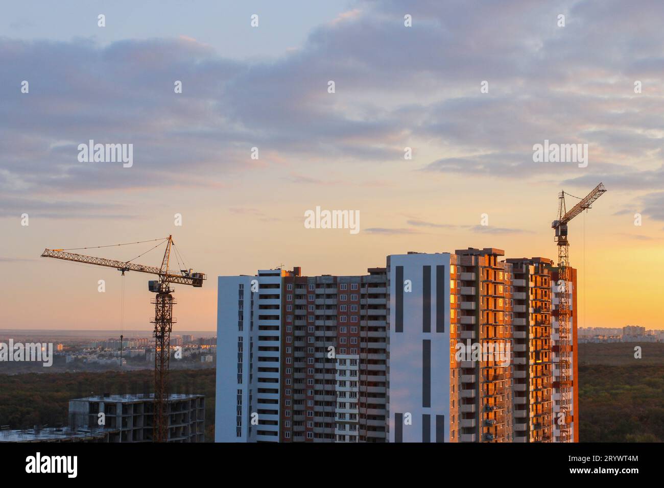 Hochhauskräne arbeiten in der Nähe von Häusern im Bau Stockfoto