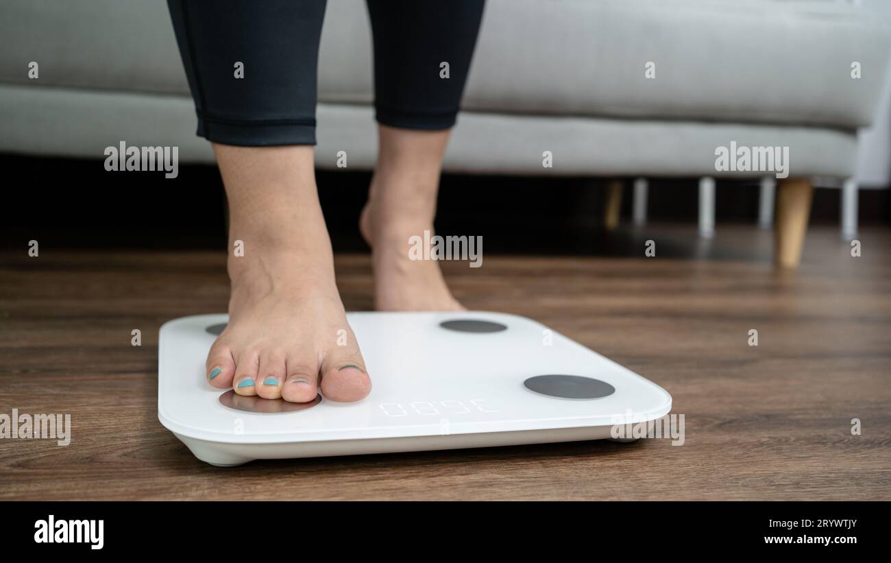 Füße stehen zur Gewichtskontrolle auf einer elektronischen Waage. Messgerät in Kilogramm für eine Diätkontrolle Stockfoto