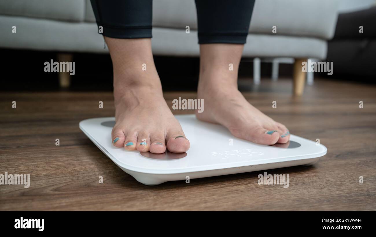 Füße stehen zur Gewichtskontrolle auf einer elektronischen Waage. Messgerät in Kilogramm für eine Diätkontrolle Stockfoto