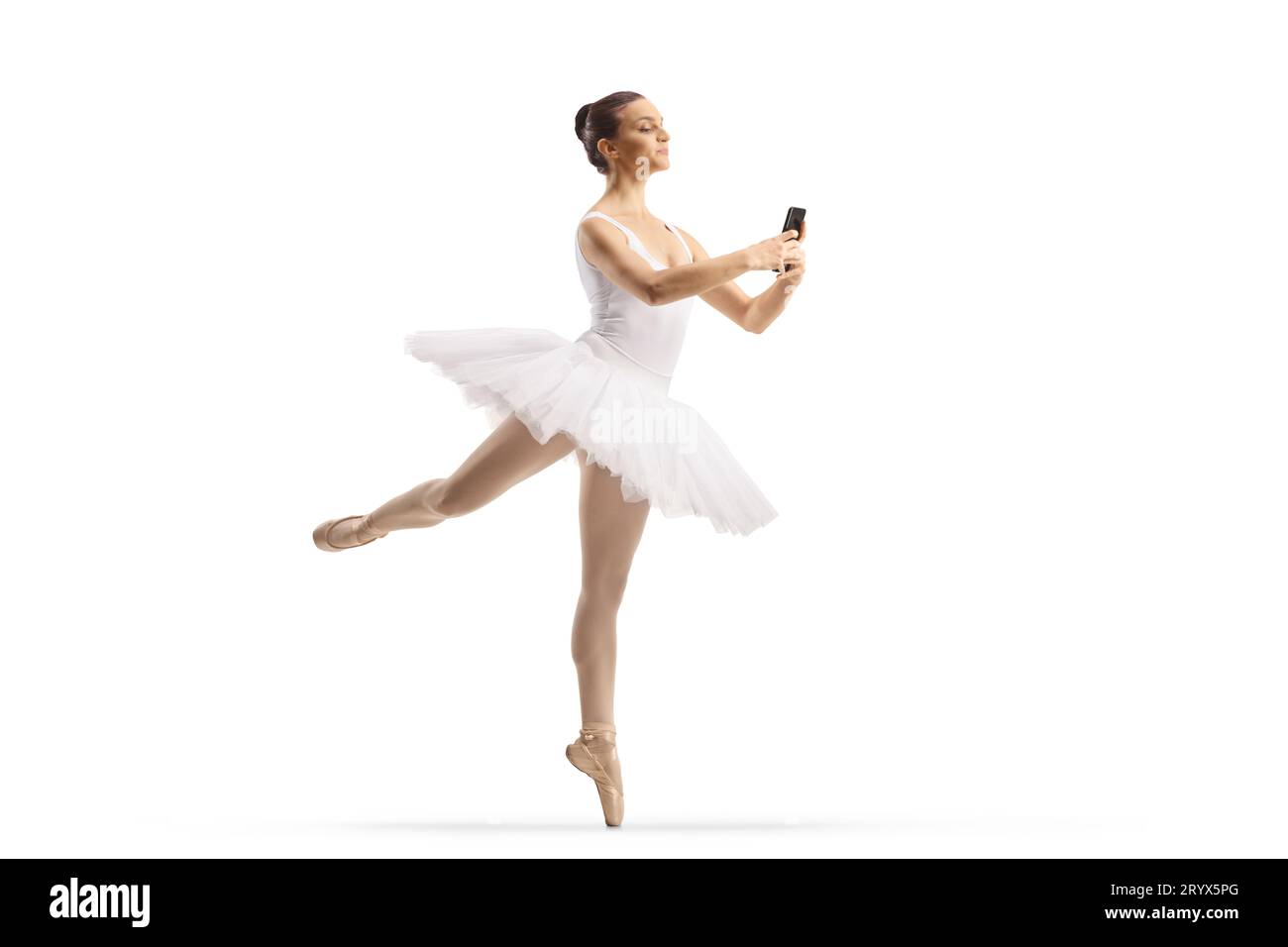 Aufnahme einer Ballerina in voller Länge, die auf weißem Hintergrund tanzt und ein Smartphone isoliert hält Stockfoto