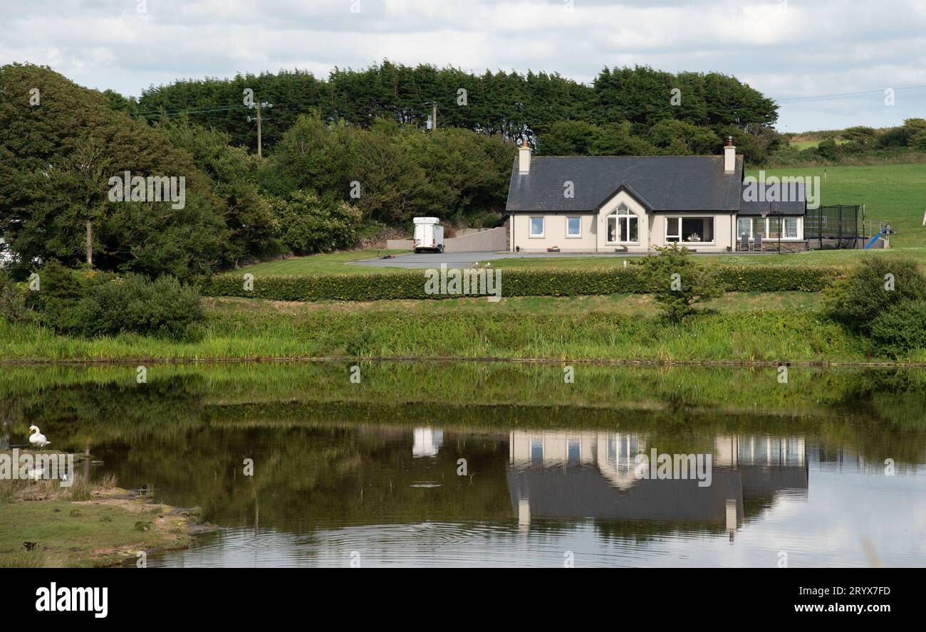 Traditionelles Landhaus in der Natur spiegelt sich in einem See wider. Friedlicher Lebensstil im Freien Stockfoto