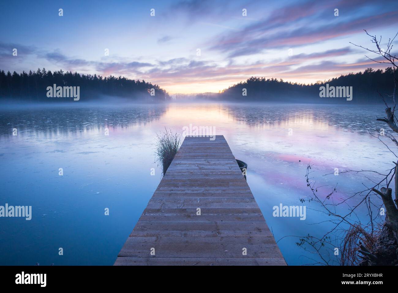 Eine malerische hölzerne Bootsanlegestelle, die sich in das ruhige, kristallklare Wasser eines Sees erstreckt Stockfoto