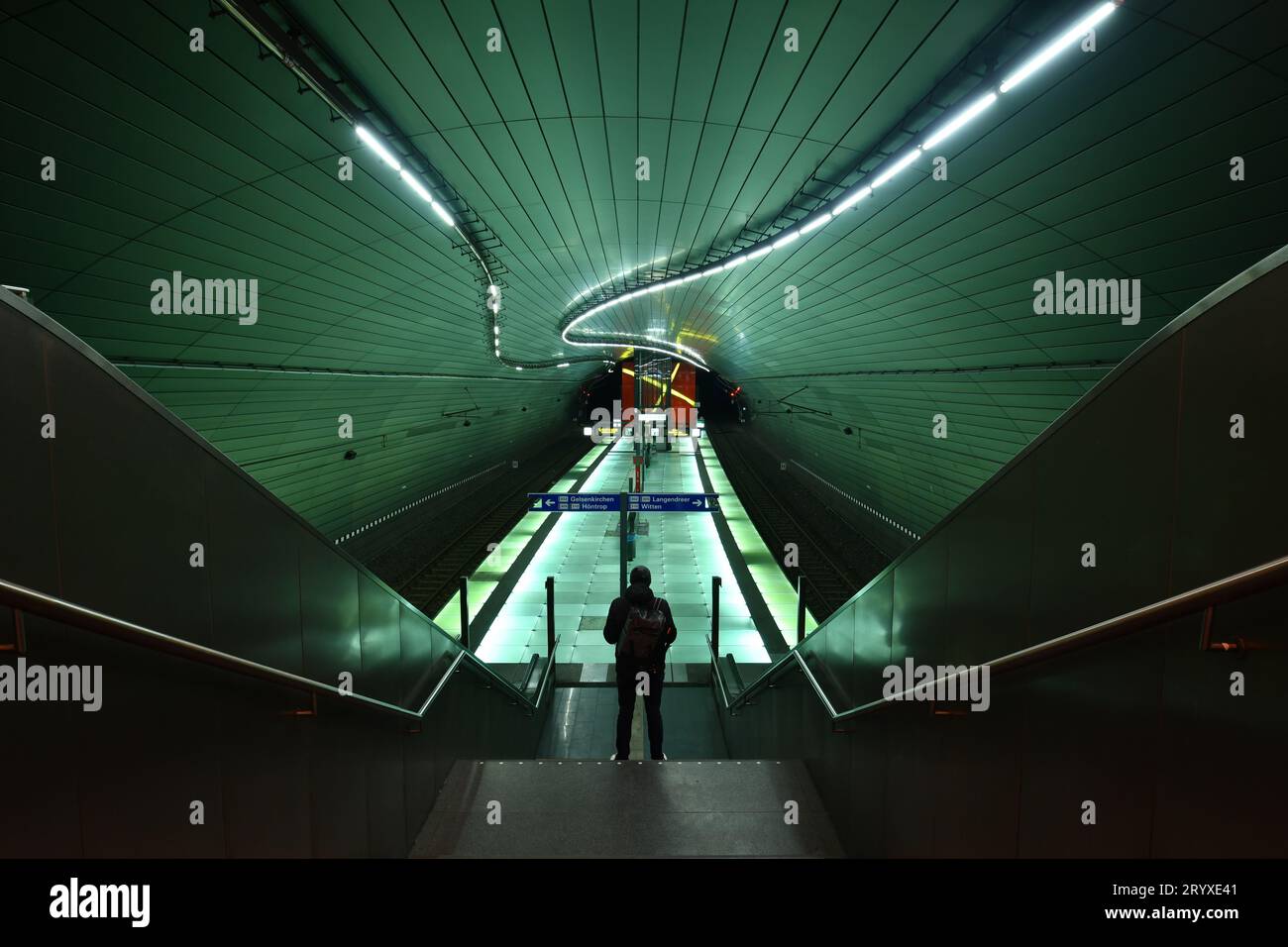 Rückansicht eines Mannes, der auf einer Treppe in einer beleuchteten U-Bahn-Station Lohring in Bochum steht Stockfoto