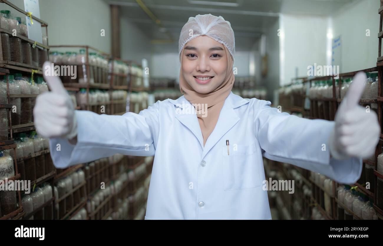 Porträt einer jungen asiatischen muslimischen Wissenschaftlerin, die in einer Pilzfabrik forscht und Pilzsäuerungsmittel in einer Str. untersucht Stockfoto