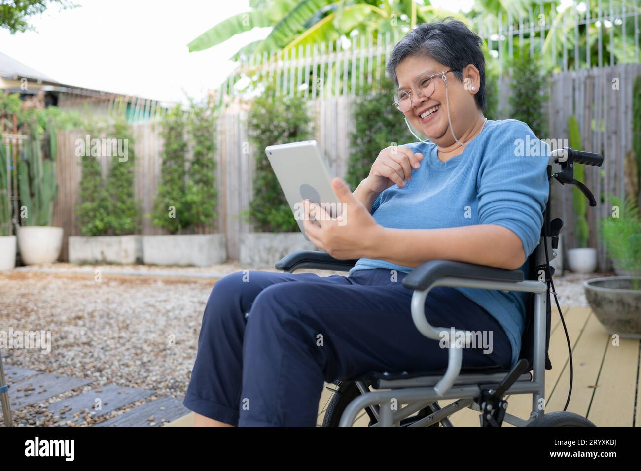 Glückliche Seniorin im Rollstuhl mit digitalem Tablet zu Hause. Stockfoto