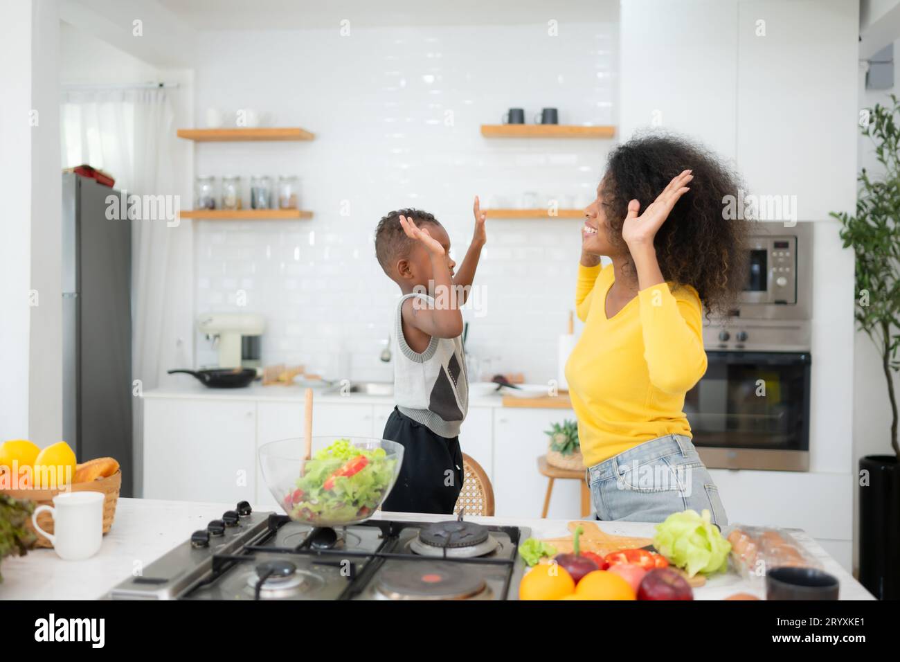 Afroamerikaner Mutter und Sohn bereiten gemeinsam Salat in der Küche zu Hause vor Stockfoto