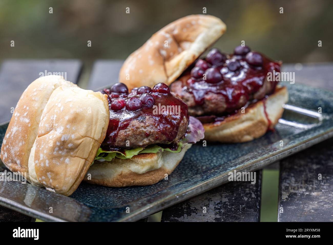 Frische gegrillte Rindfleischburger mit Huckleberry bbq Sauce und frischen Hucklebeeren serviert im Freien Stockfoto