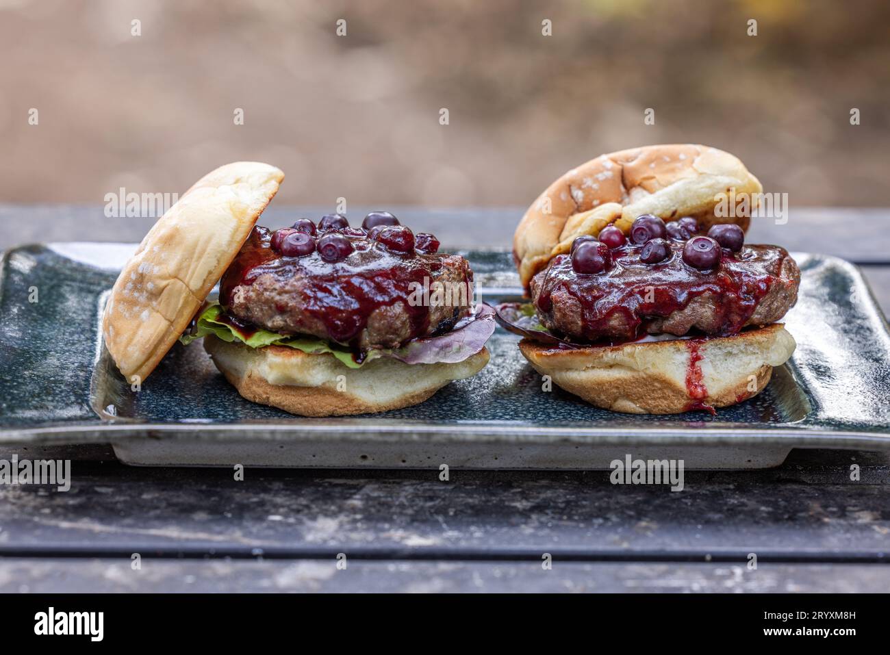 Frische gegrillte Rindfleischburger mit Huckleberry bbq Sauce und frischen Hucklebeeren serviert im Freien Stockfoto