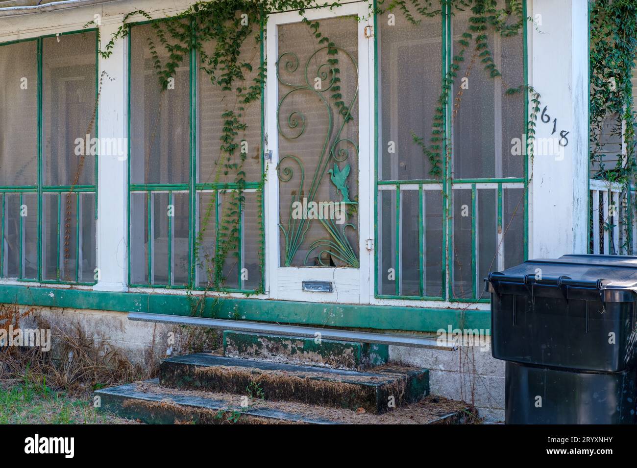 NEW ORLEANS, LA, USA - 21. SEPTEMBER 2023: Tür mit Retro-Bildschirm auf der alten, abgenutzten Veranda des Bungalows in Uptown Stockfoto