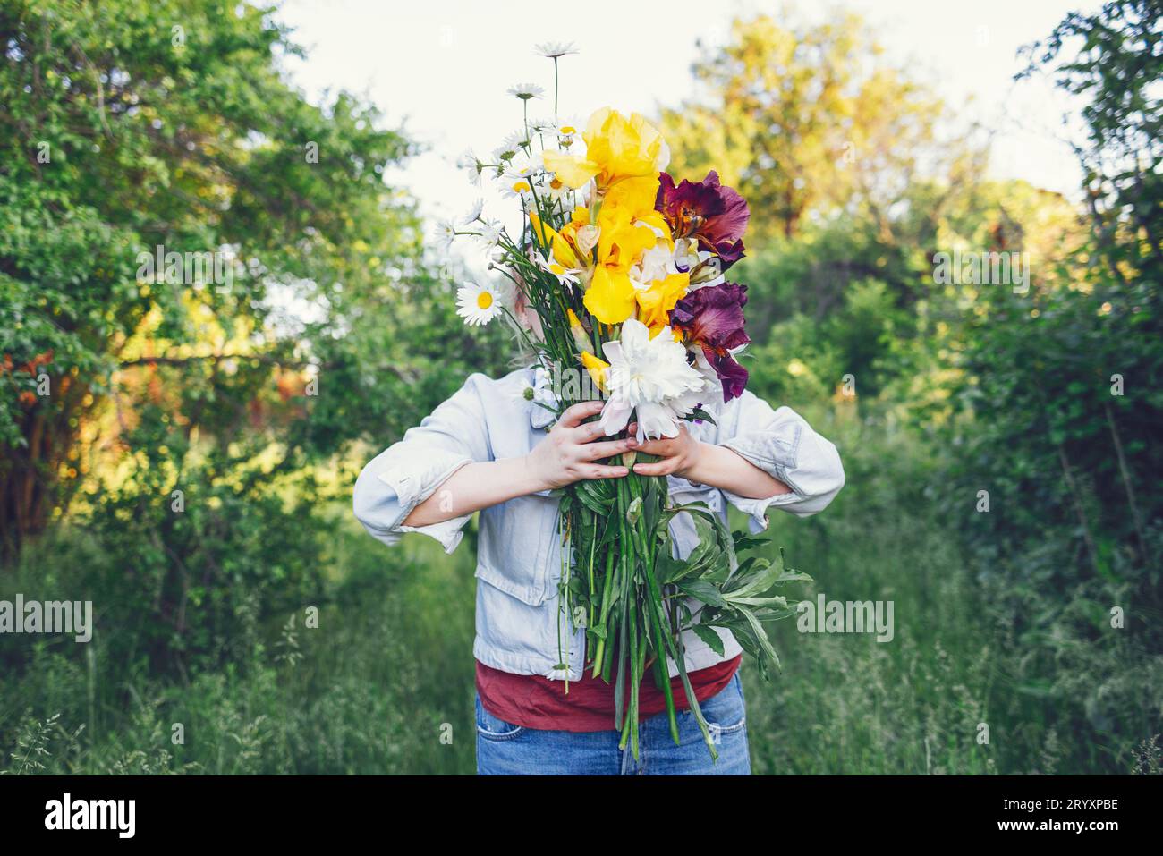 Eine junge Frau bedeckte ihr Gesicht mit einem großen Blumenstrauß. Stockfoto