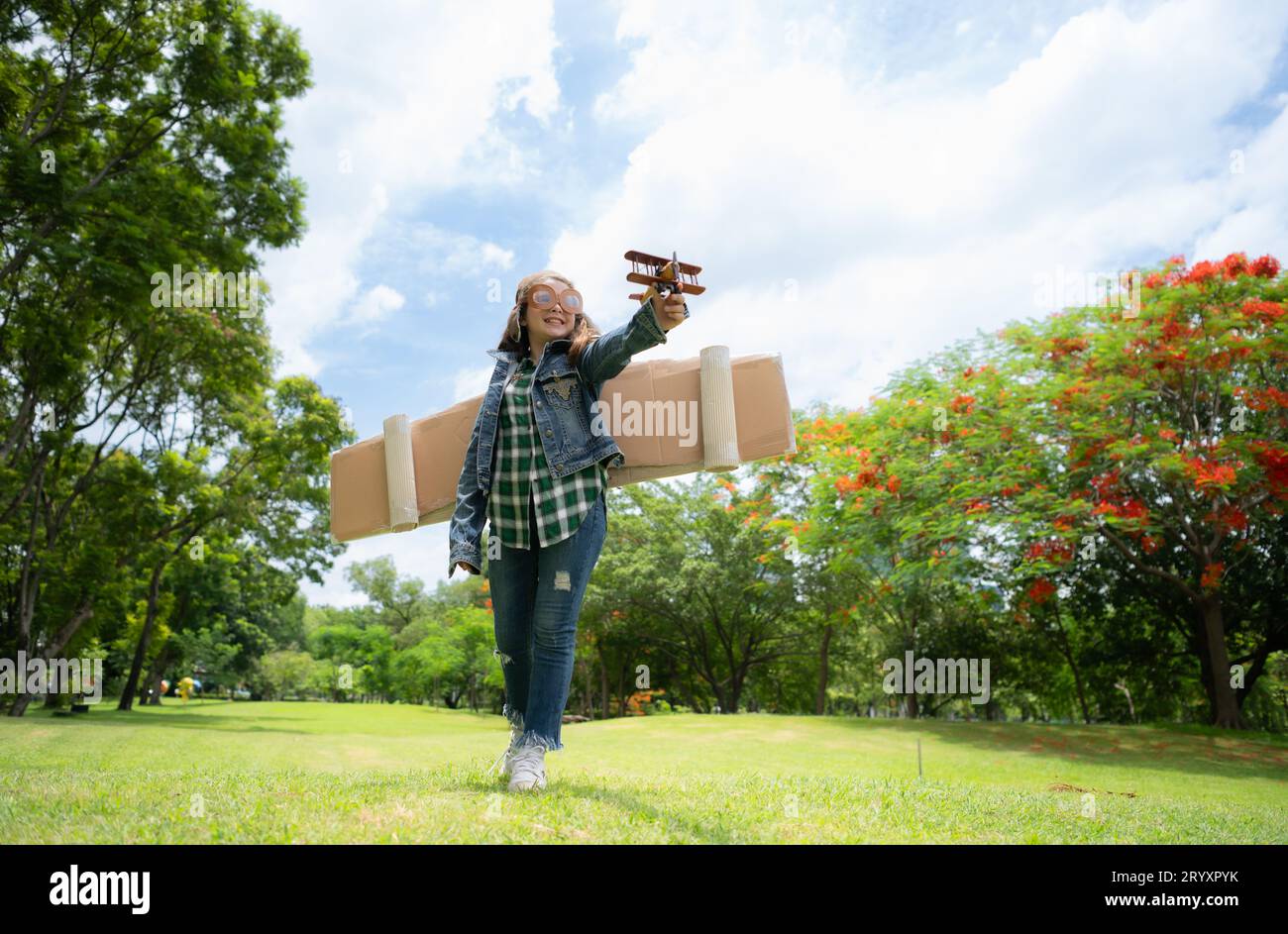 Ein kleines Mädchen im Urlaub im Park mit einem Piloten-Outfit und fliegender Ausrüstung. Lauf herum und hab Spaß mit ihren Träumen. Stockfoto