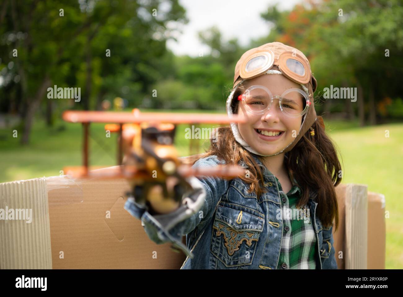 Ein kleines Mädchen im Urlaub im Park mit einem Piloten-Outfit und fliegender Ausrüstung. Lauf herum und hab Spaß mit ihren Träumen. Stockfoto