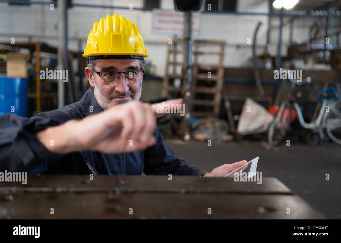 Ein älterer Techniker verwendet einen Computer, um die Betriebssteuerung einer Stanzmaschine aus Stahl zu testen. Stockfoto