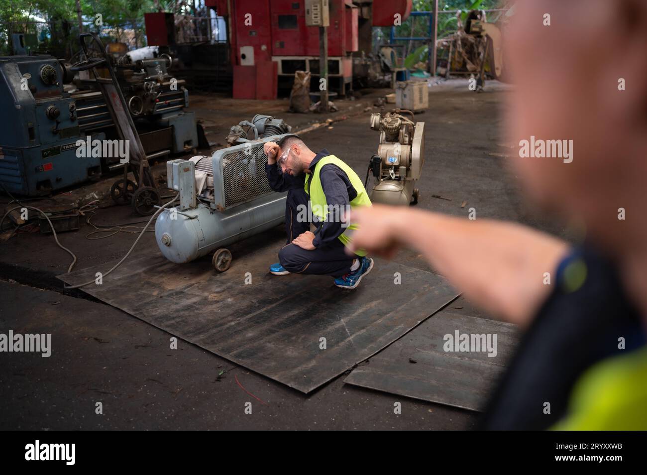 Der Teamleiter des Technikers ermutigt das Team, das von harter Arbeit müde ist. Bei der Reparatur alter Maschinen, um zum normalen Betrieb zurückzukehren Stockfoto