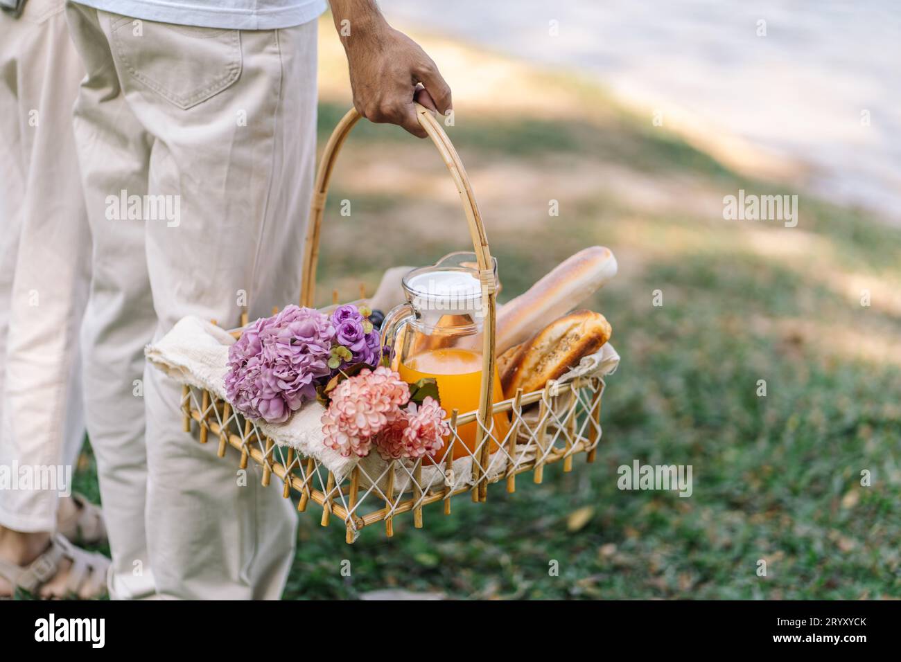 Pärchen, die im Garten mit Picknickkorb laufen. In Love Pärchen genießen Picknick-Zeit im Park im Freien Stockfoto