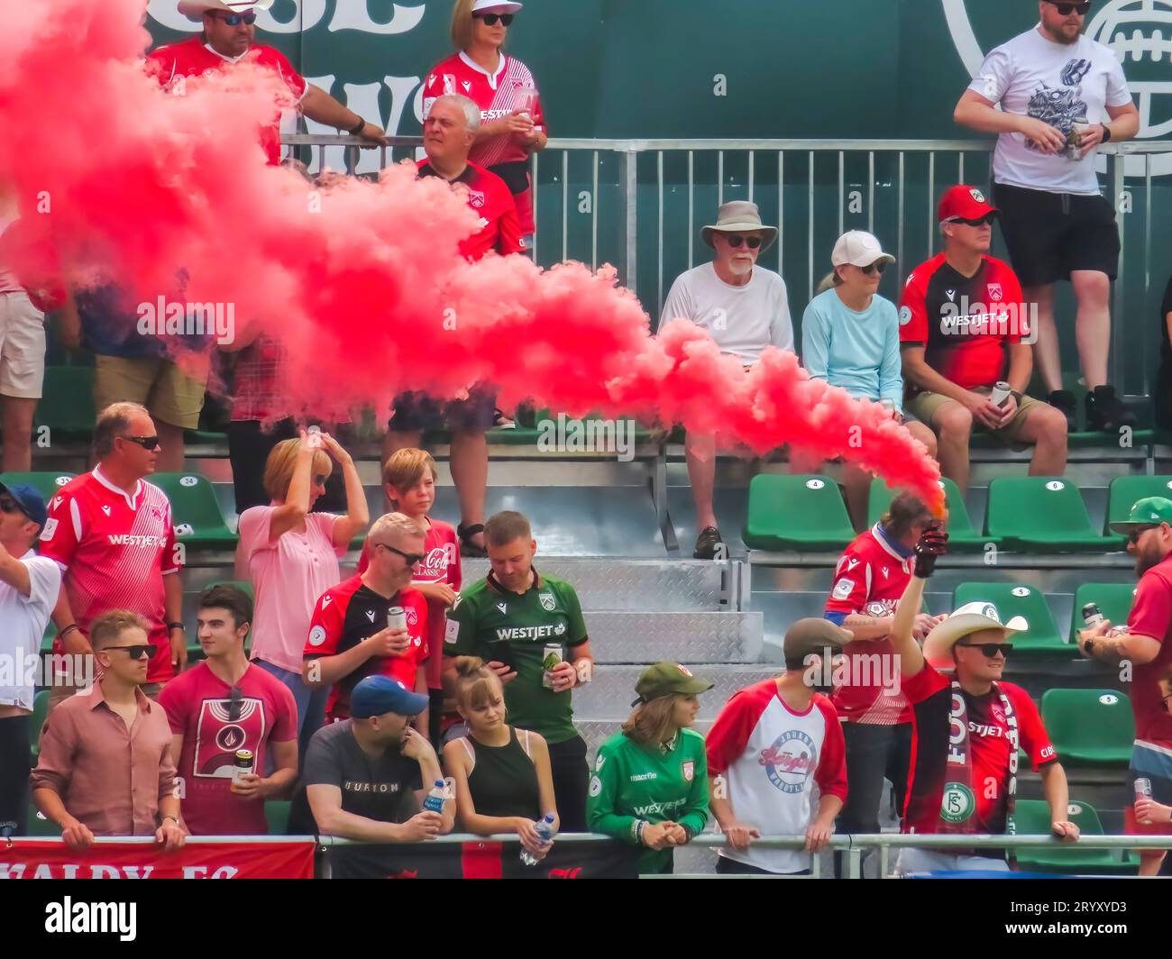 Calgary, Alberta, Kanada. Juli 2023. Ein Fußballfan, der während eines Spiels eine Farb-Rauchbombe hält. Konzept: Fan-Leidenschaft, Menschenmassen Stockfoto