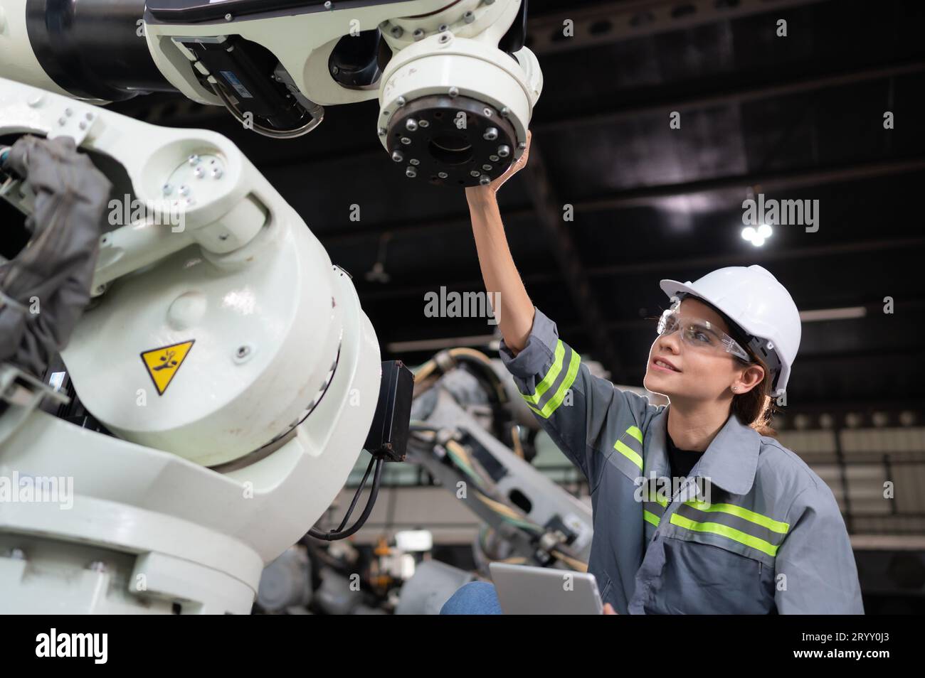 Eine Ingenieurin installiert ein Programm auf einem Roboterarm in einem Roboterlager. Und prüfen Sie die Funktion, bevor Sie die Maschine t senden Stockfoto