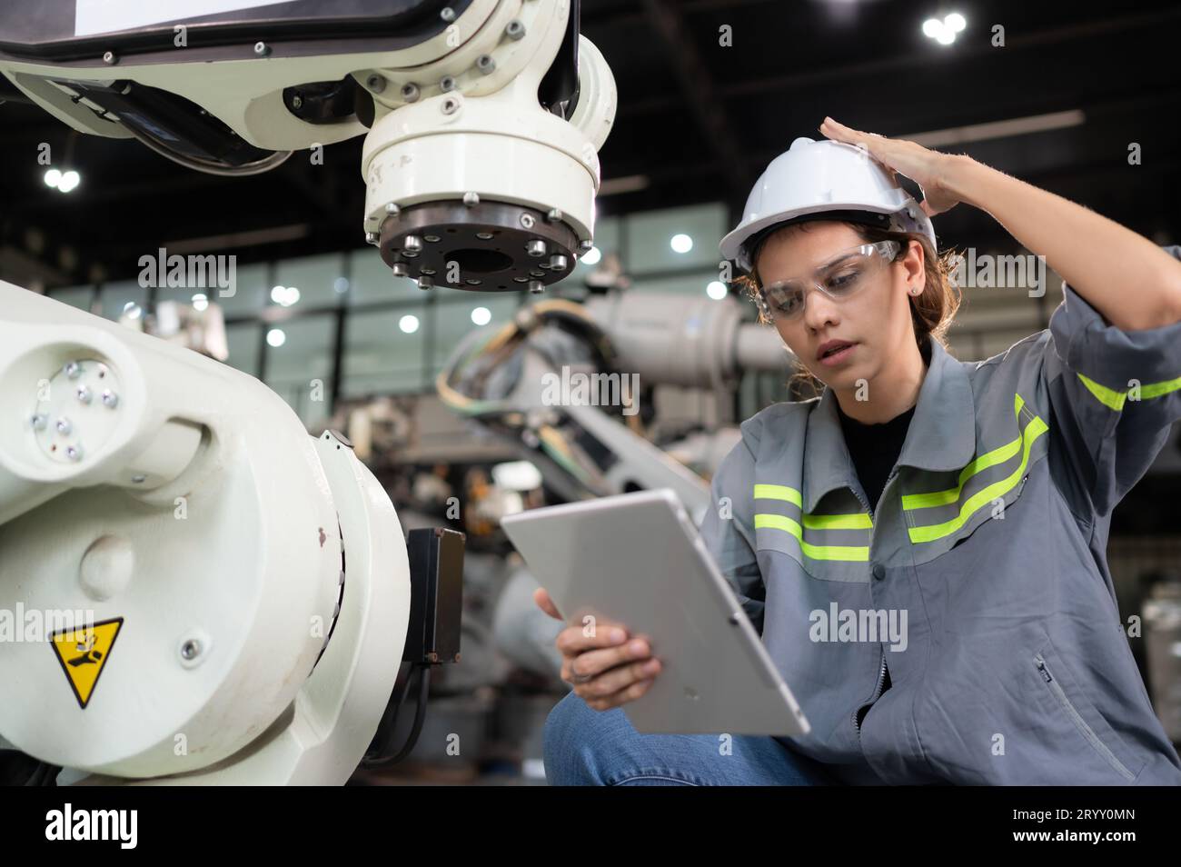 Eine Ingenieurin installiert ein Programm auf einem Roboterarm in einem Roboterlager. Und prüfen Sie die Funktion, bevor Sie die Maschine t senden Stockfoto