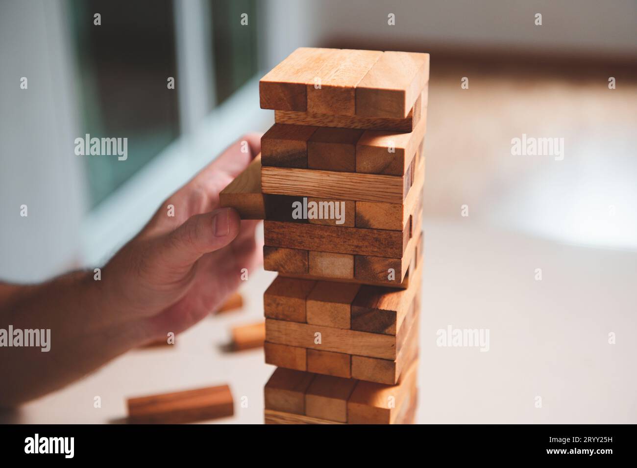 Holzblöcke Spielzeug Puzzle mit menschlicher Hand auf dem Tisch zu Hause Hintergrund. Unterhaltungs- und Geschäftskonzept. Stockfoto