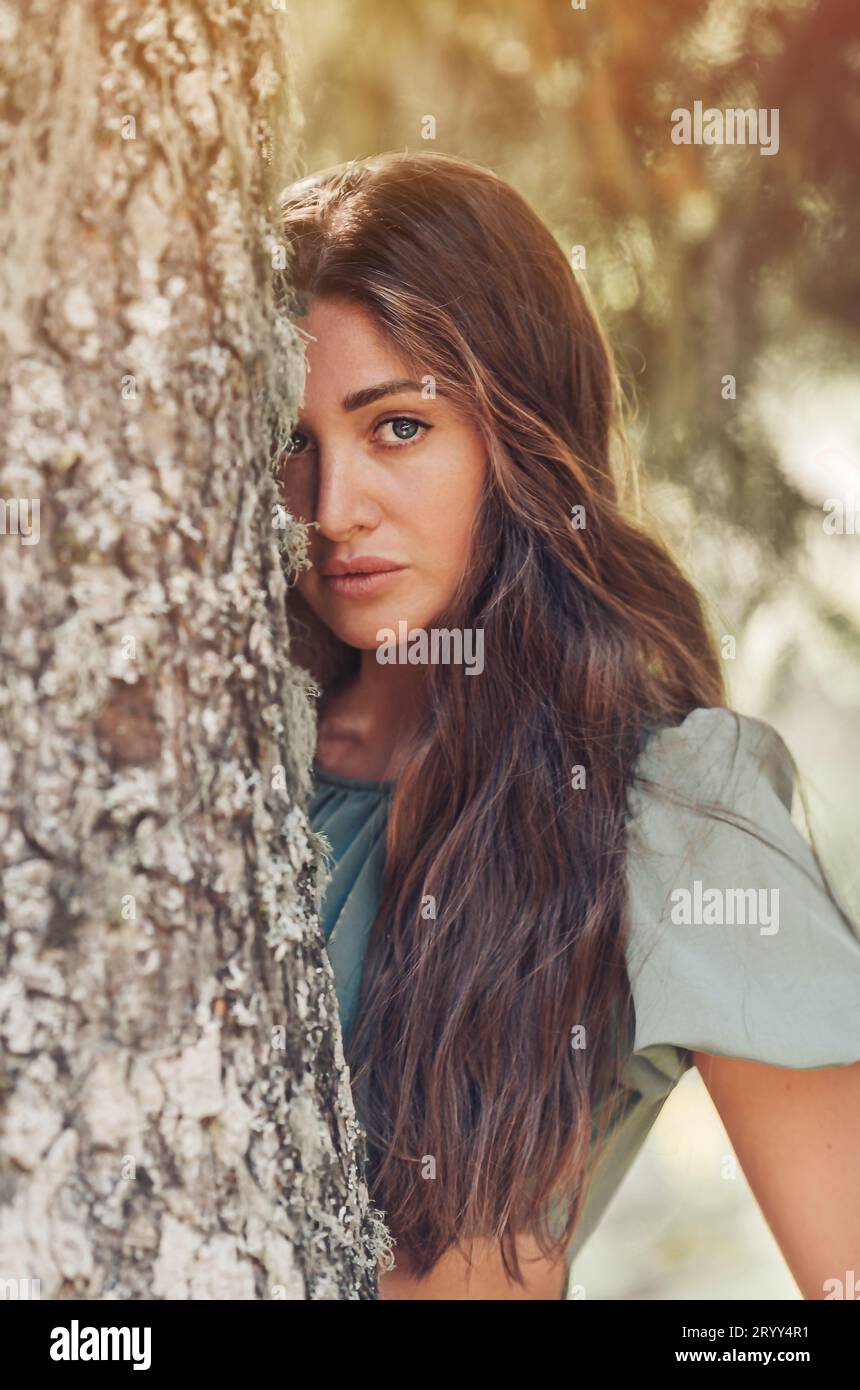 Porträt der schönen jungen Frau im Wald. Frau steht neben dem Baum Stockfoto