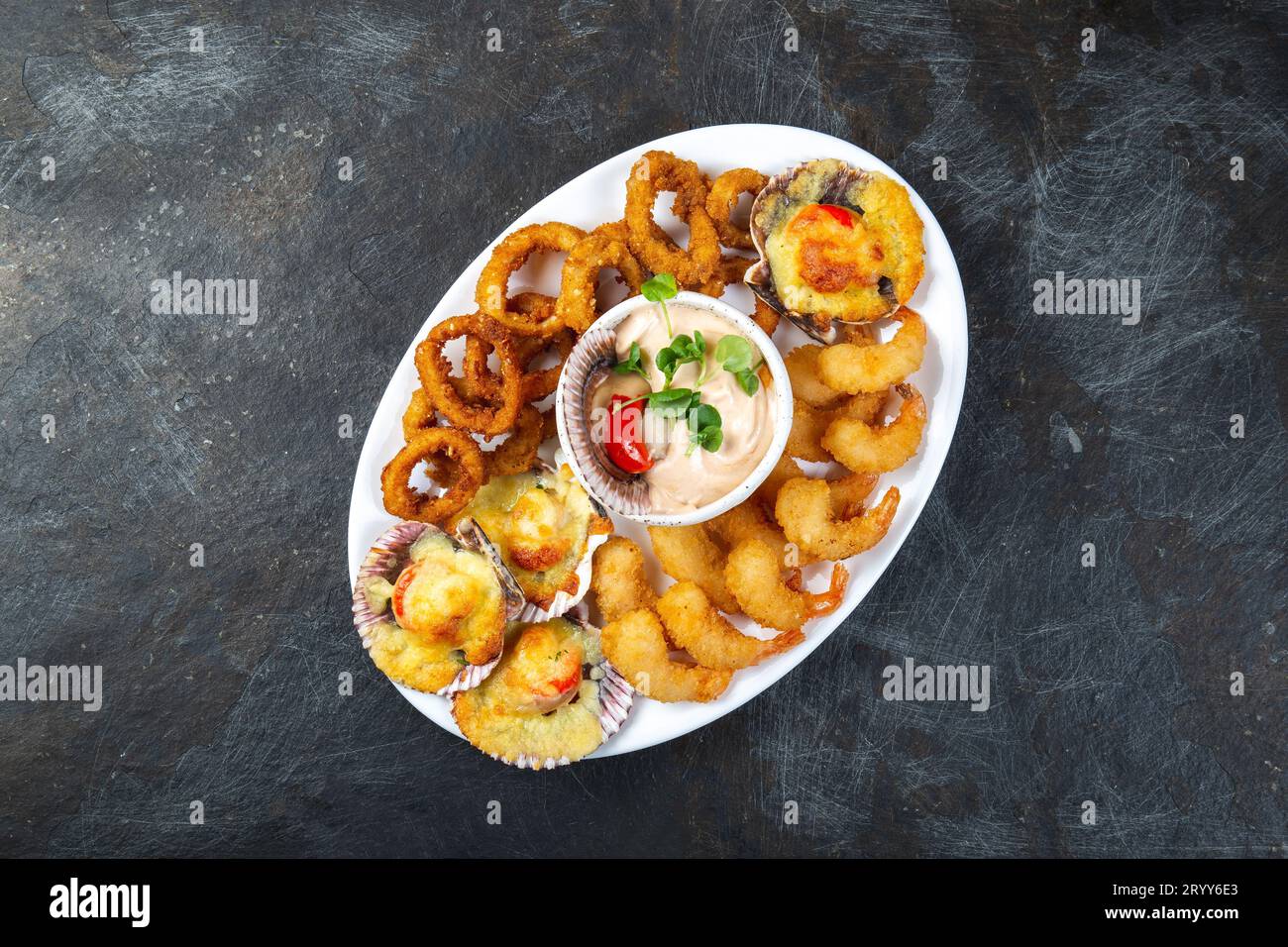 Peruanisches Essen. Piqueo Caliente. Heiße Platte mit Meeresfrüchten gebratene Garnelen, Tintenfisch Ringe und gebackene Jakobsmuscheln mit Sauce Stockfoto