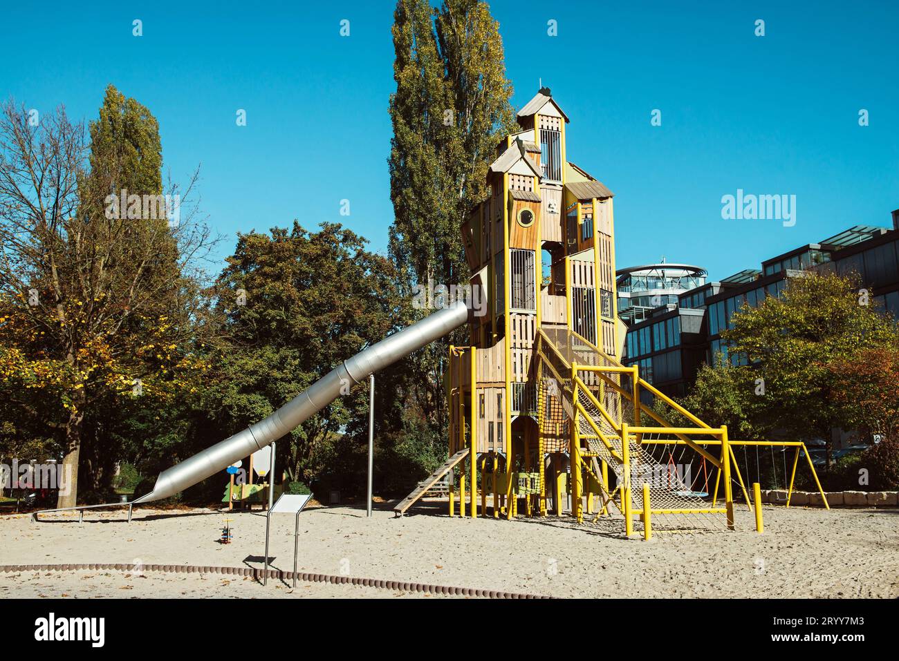 Moderner Kinderspielplatz für Outdoor-Spiele, ein Rutschrohr aus Metall, Pyramiden aus Holz, Gummibeschichtung auf dem playgro Stockfoto