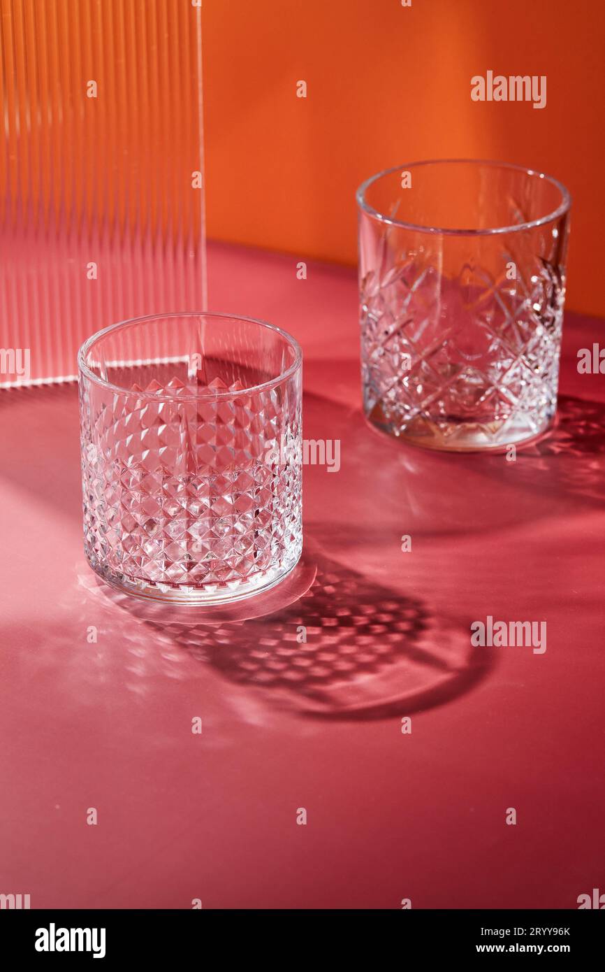 Zwei leere Glasgläser auf farbigem Hintergrund mit Schatten von Sonnenlicht Stockfoto