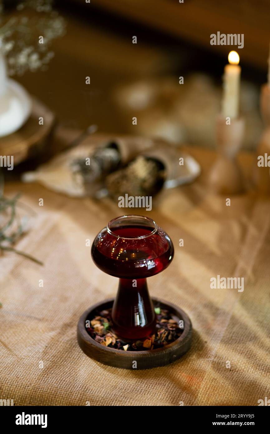 Wintertee wird in einer Tasse serviert, die in einer warmen und einladenden Atmosphäre bei Kerzenlicht steht. Präsentiert auf einem Holztisch mit Sackleinen-Textur Stockfoto