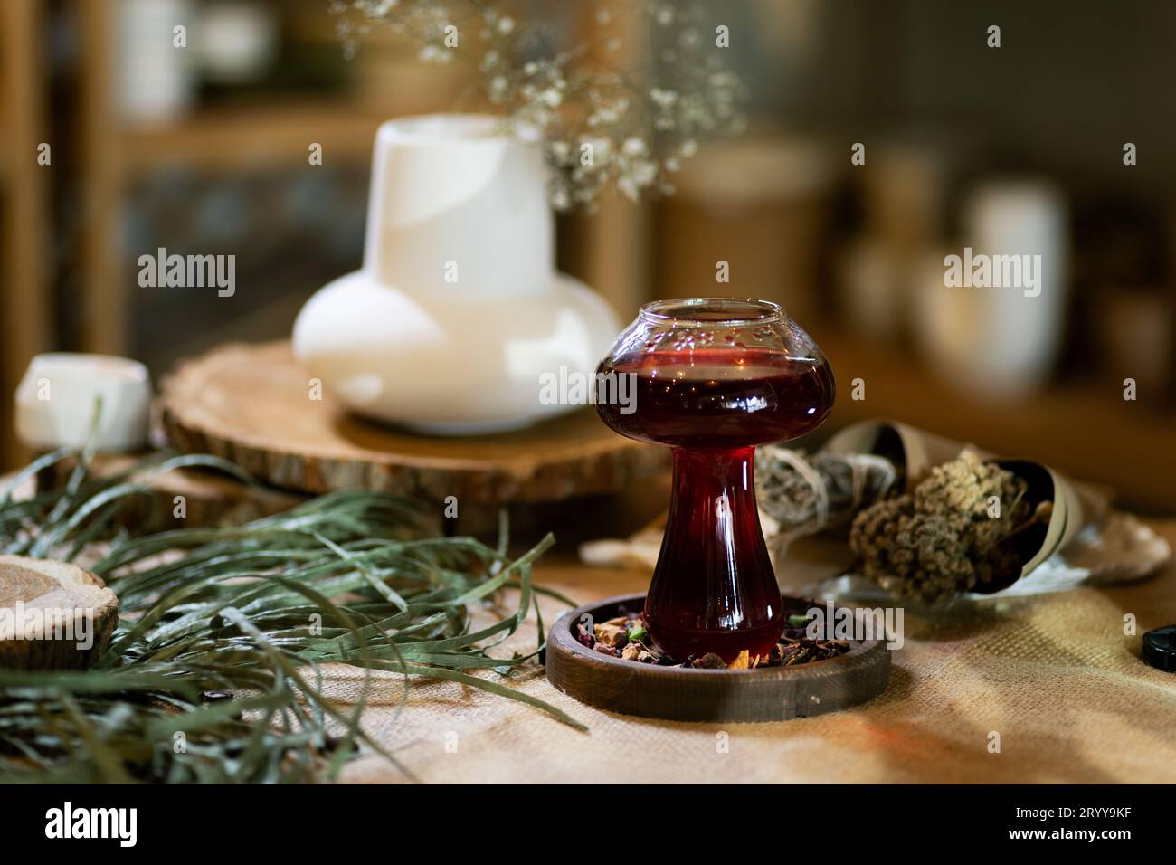 Wintertee wird in einer Tasse serviert, die in einer warmen und einladenden Atmosphäre bei Kerzenlicht steht. Präsentiert auf einem Holztisch mit Sackleinen-Textur Stockfoto