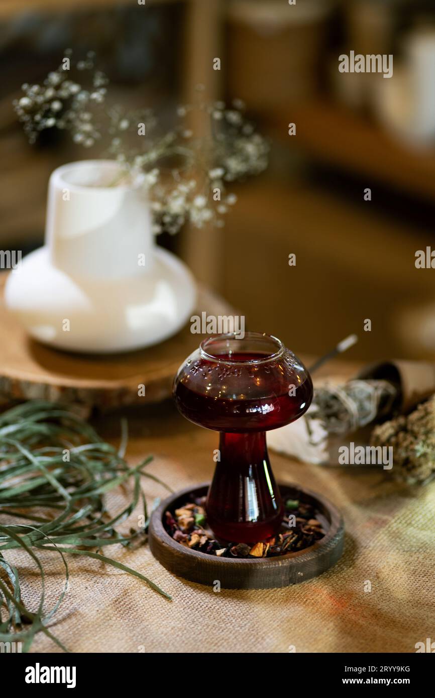 Wintertee wird in einer Tasse serviert, die in einer warmen und einladenden Atmosphäre bei Kerzenlicht steht. Präsentiert auf einem Holztisch mit Sackleinen-Textur Stockfoto
