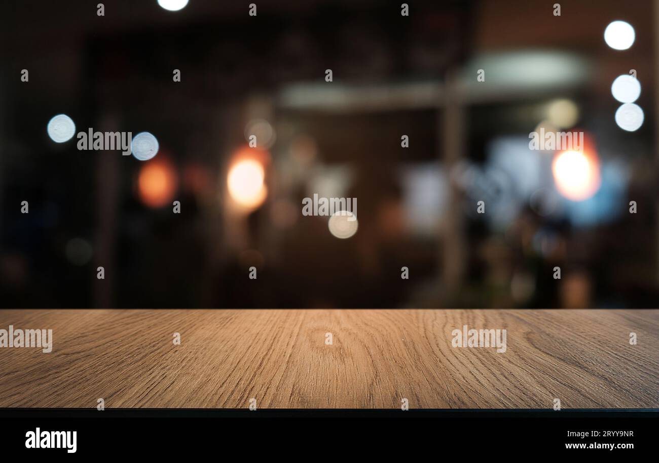 Leerer dunkler Holztisch vor dem abstrakten, verschwommenen Bokeh-Hintergrund des Restaurants. Kann zur Anzeige oder Montage Ihres PR Stockfoto