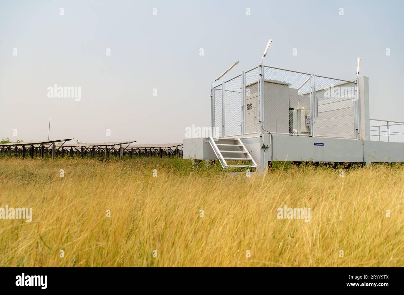 Das Feld der Solarpaneele mit einer Energiespeicherstation, die sich in der Mitte eines Solarzellenpaneels auf einer Fläche von Hunderten von A befindet Stockfoto