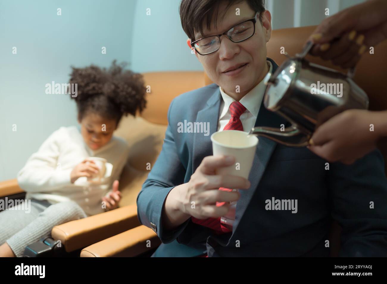 Die Flugbegleiterin serviert den Passagieren der Business Class Getränke Stockfoto