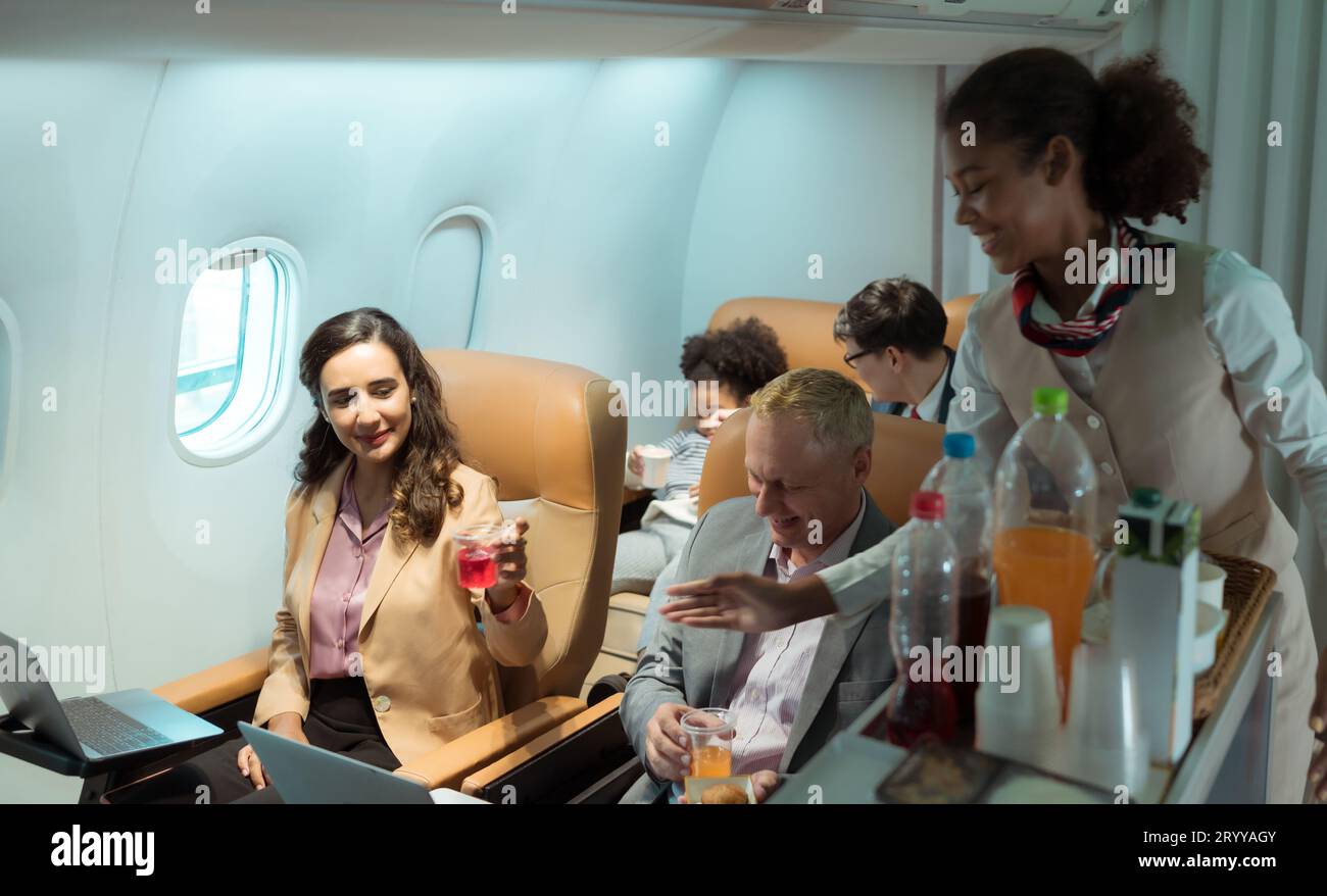 Die Flugbegleiterin serviert den Passagieren Speisen und Getränke Stockfoto