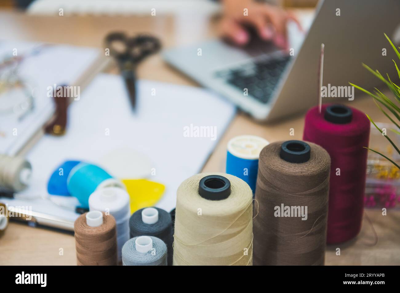 Nahaufnahme der Nähausrüstung auf dem Tisch der Modedesigner-Stylistin. Modedesigner Hand in der Heimwerkstatt. Elegantes fa Stockfoto