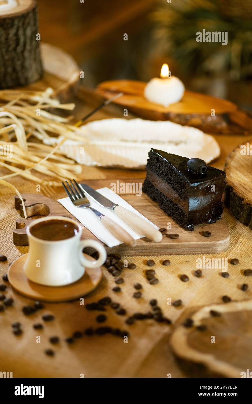 Schokoladenkuchen und türkischer Kaffee, angereichert mit verstreuten Kaffeebohnen. Die Umgebungsbeleuchtung hebt die Texturen hervor. Stockfoto