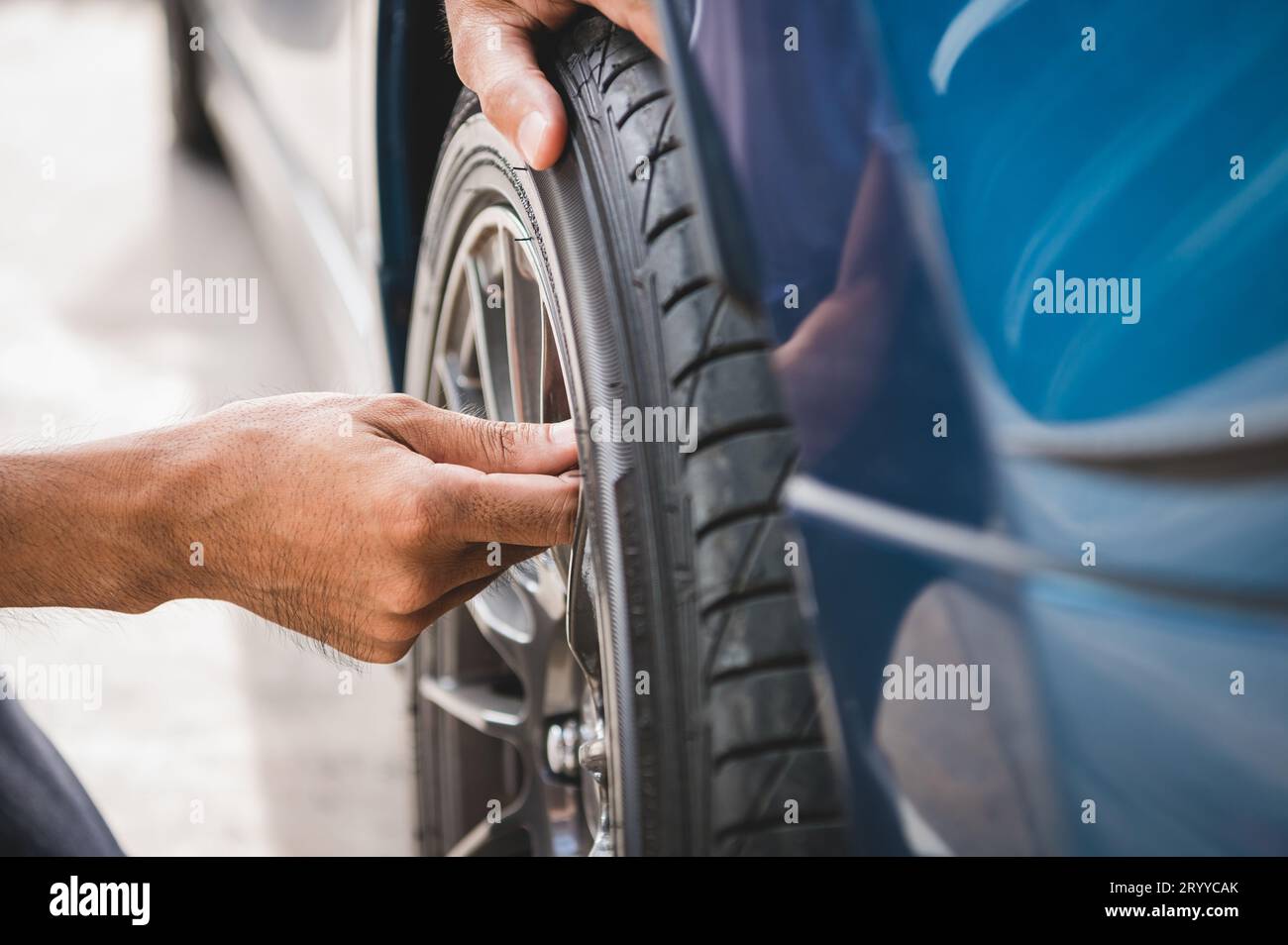 Nahaufnahme männlicher Kfz-Techniker, der Reifenventil-Stickstoffkappe für Reifenaufblasservice in Garage oder Tankstelle entfernt. Autoherr Stockfoto