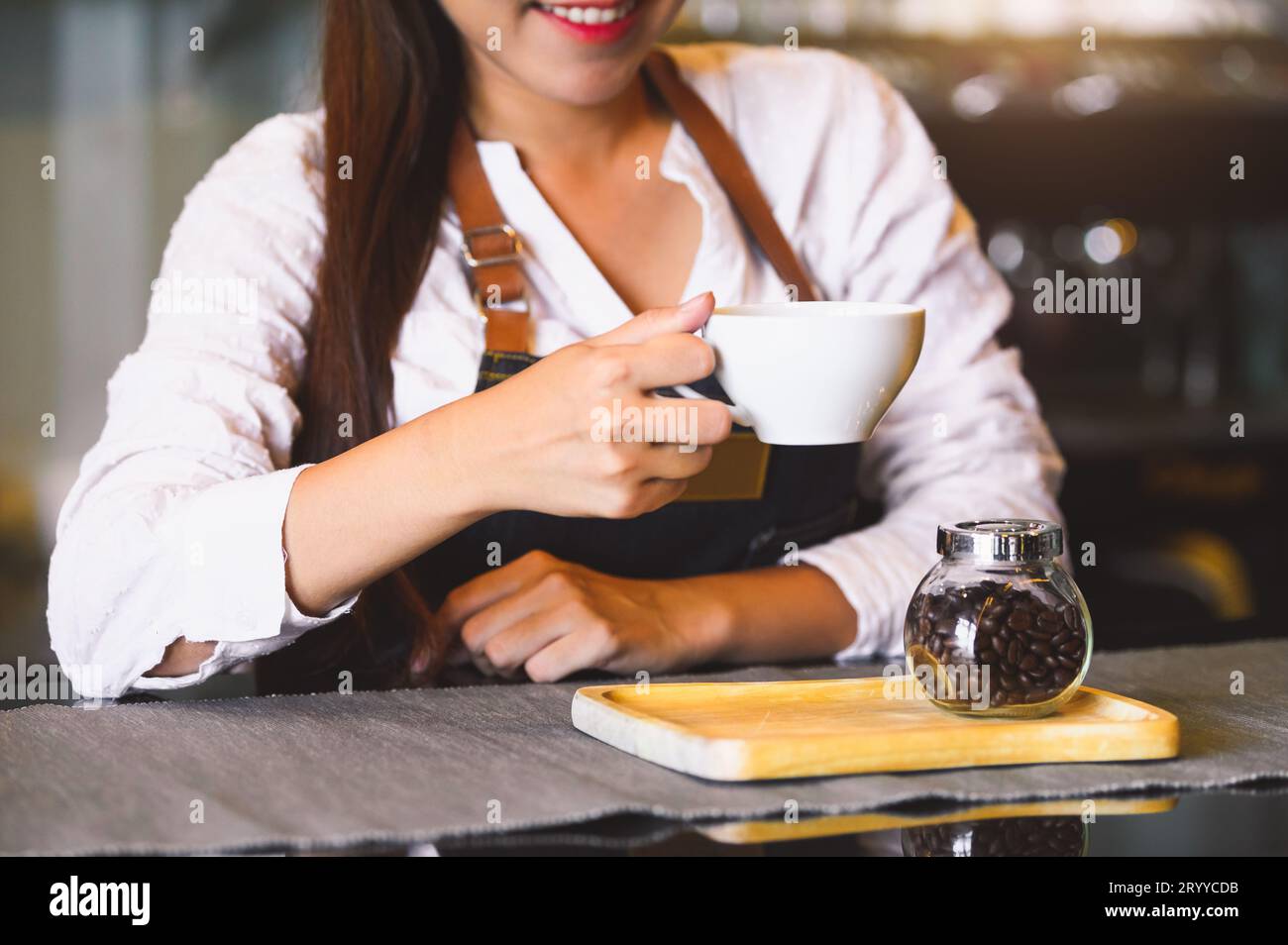 Nahaufnahme einer weißen Kaffeetasse mit einer schönen asiatischen Frau Barista Hintergrund für das Servieren an die Gäste. Tätigkeit und Beruf. Essen und Stockfoto