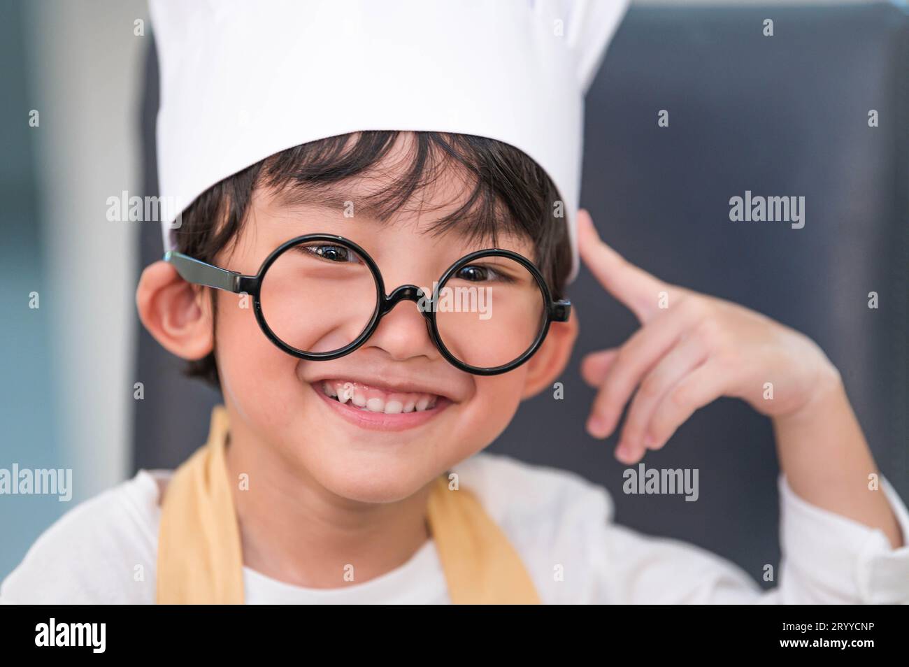 Porträt süßer kleiner asiatischer Glücksjunge, der daran interessiert ist, mit Mutter lustig in der Küche zu kochen. Lebensstil und Familie. Stockfoto
