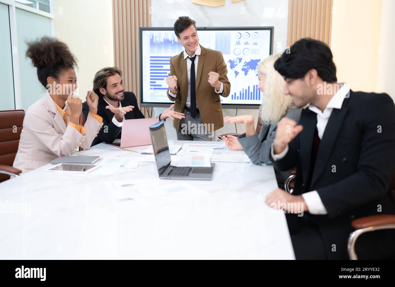 Im Tagungsraum eines internationalen Unternehmensunternehmens nimmt eine vielfältige Gruppe von Jungunternehmern mit Begeisterung auf Stockfoto