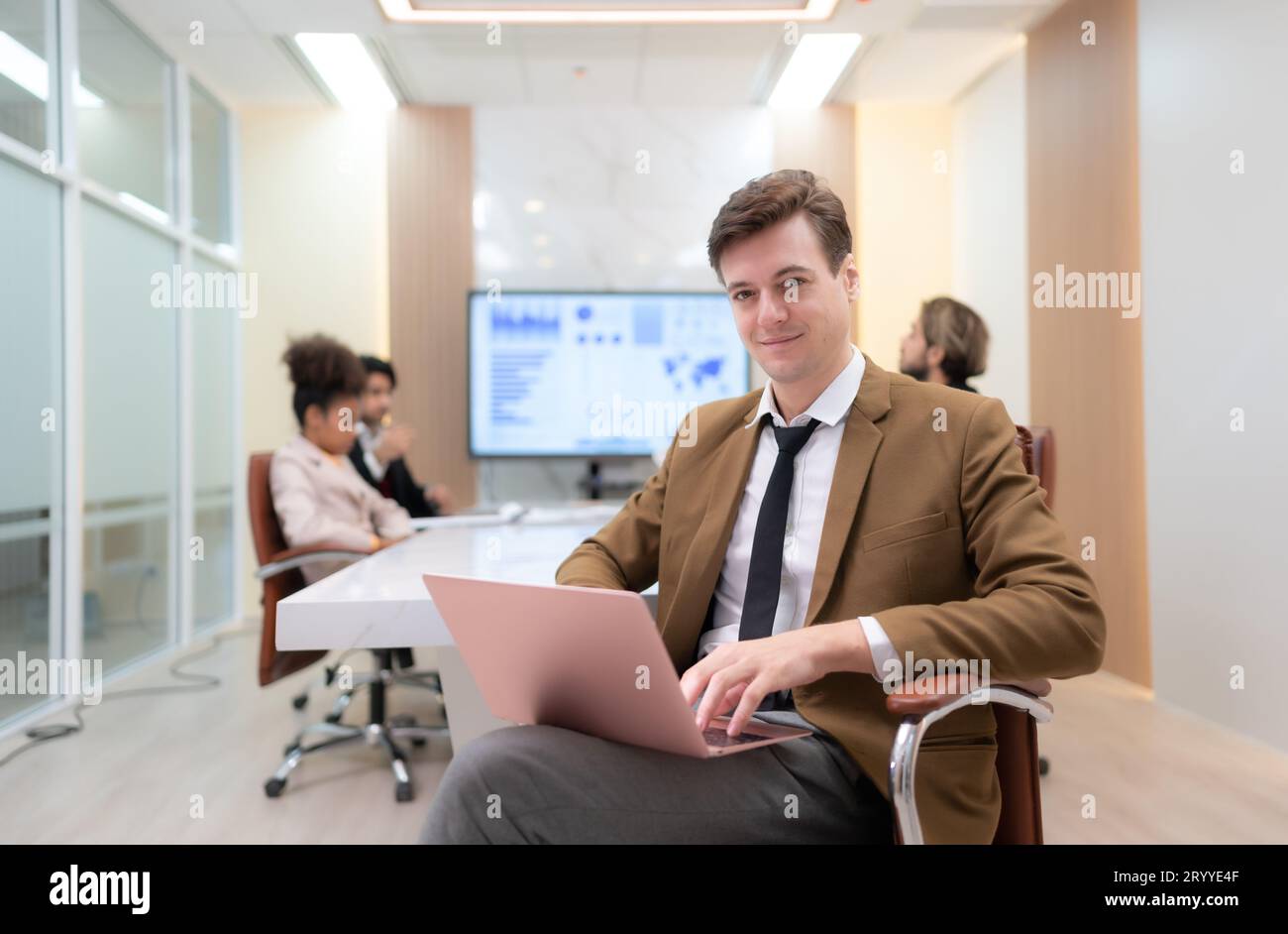 Im Tagungsraum, ein junger Geschäftsmann, der in einem geheimen Treffen mit vielen anderen Geschäftsleuten sitzt, ist die Atmosphäre glücklich Stockfoto