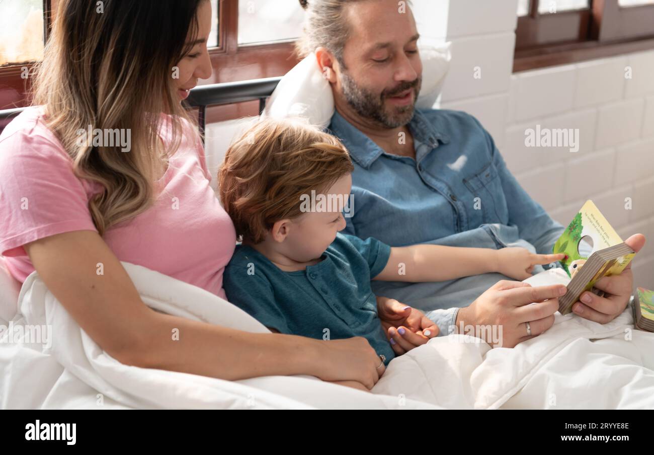 Der Vater des kleinen Jungen las den Kindern Geschichten vor, bevor er ins Bett ging, um sich zu entspannen und bis zum Morgen gut zu schlafen. Stockfoto