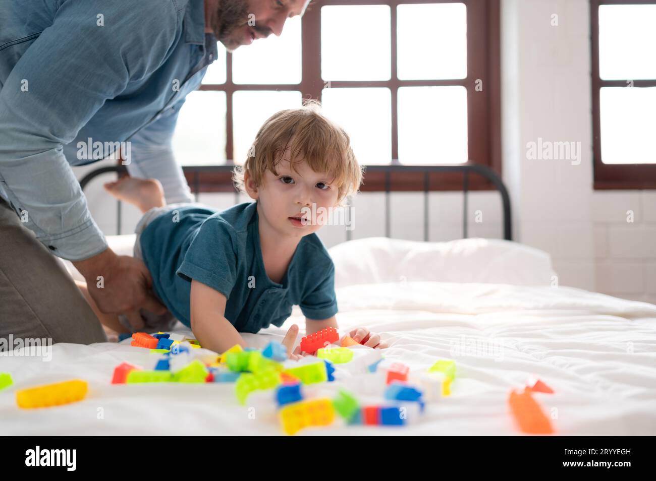 Vater und kleiner Junge haben Spaß beim Spielen mit deinen neuen Spielzeugen im Schlafzimmer. Spielzeug, das die Denkfähigkeit von Kindern verbessert Stockfoto