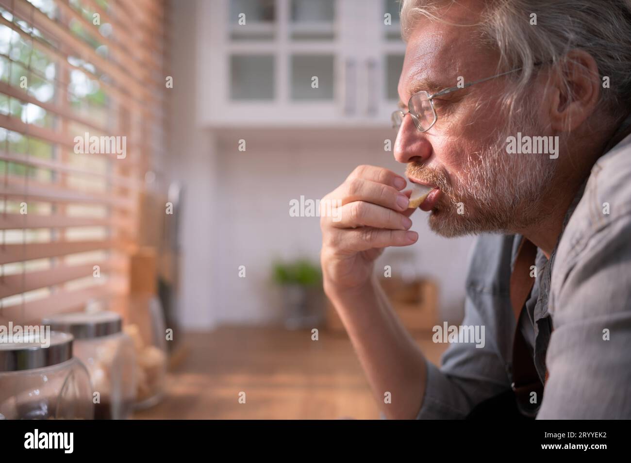 Opa in der Küche mit natürlichem Licht, bereitet sich auf das Abendessen für die Familie vor. Stockfoto