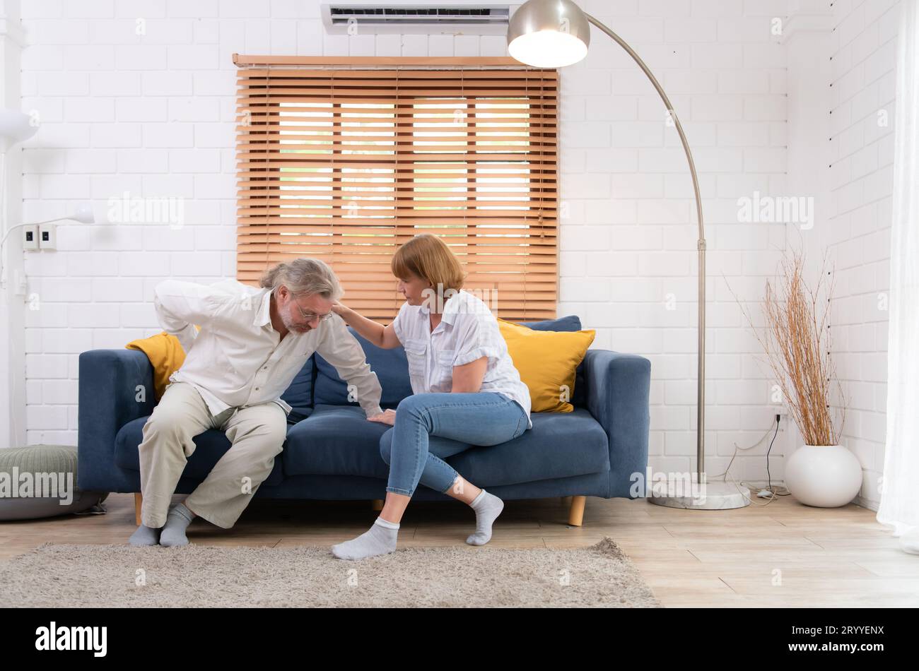 Ein älteres Ehepaar mit einem Mann, der an Rückenschmerzen leidet, ohne Kinder zu versorgen, muss jeder helfen und sich um jedes kümmern Stockfoto
